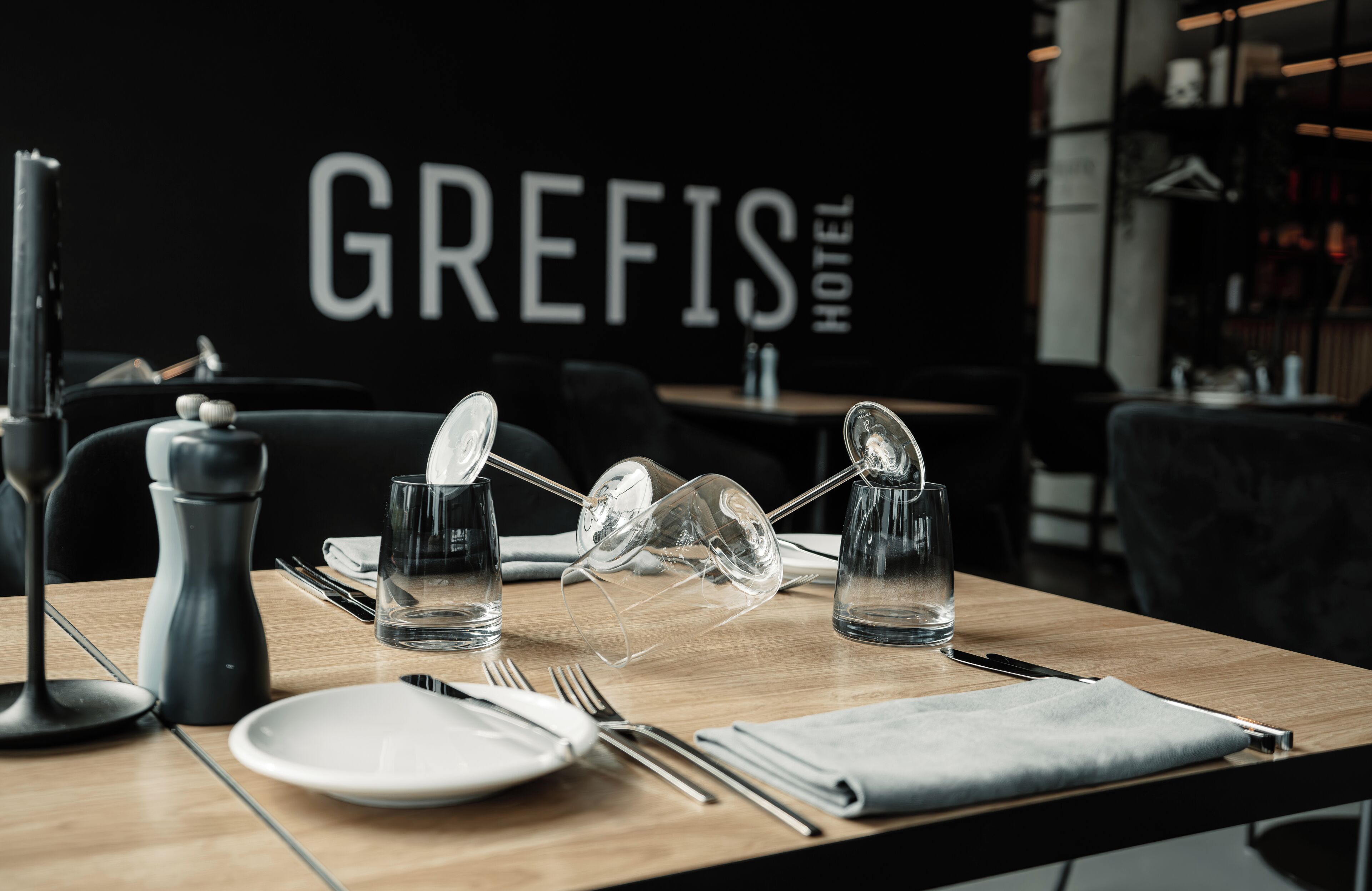 Een gedekte hotel eettafel met borden, bestek, glazen en een zout- en peperstel.