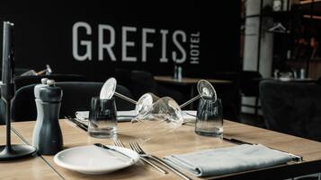 Een gedekte hotel eettafel met borden, bestek, glazen en een zout- en peperstel.