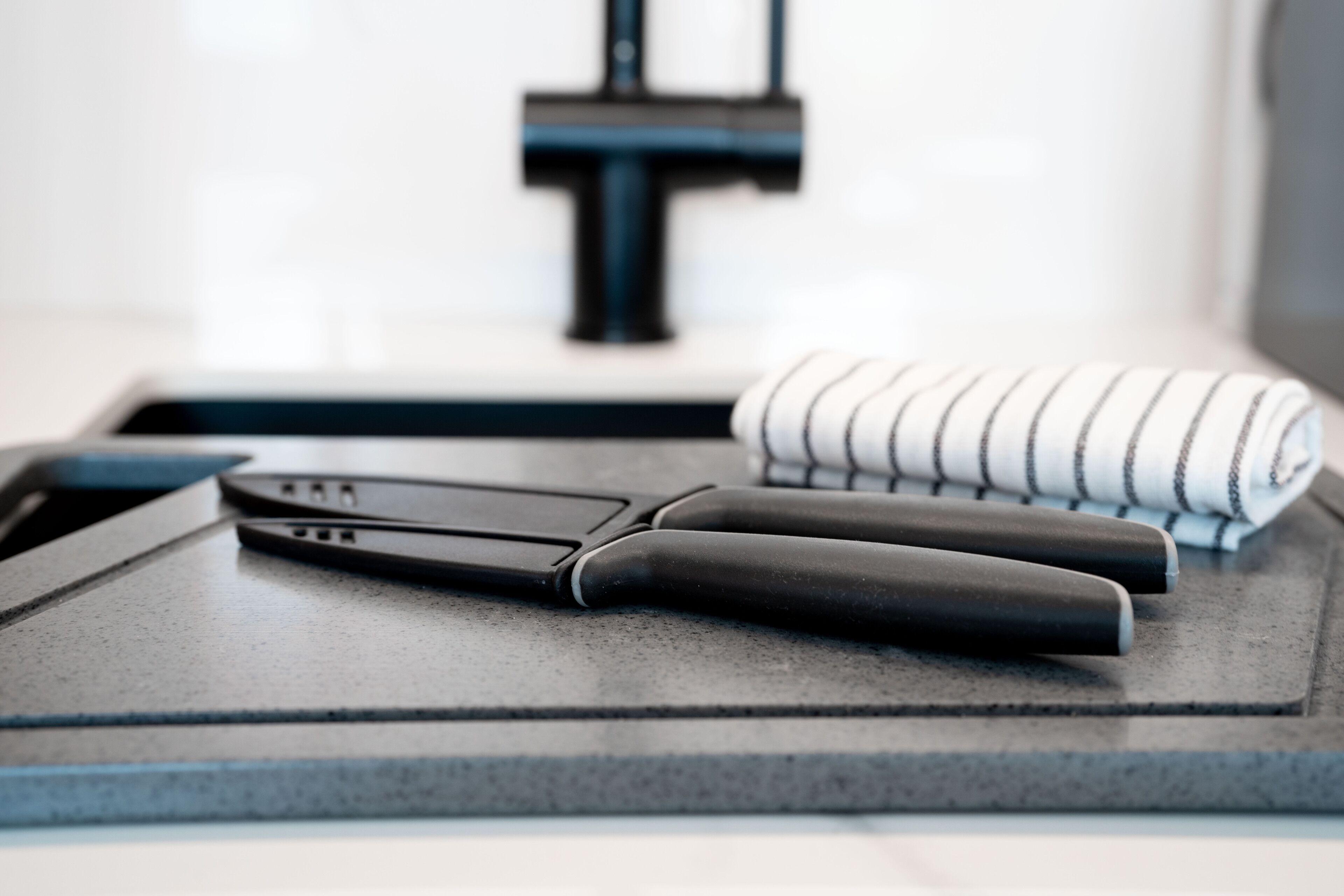 A bathroom with a towel, a black handheld showerhead, and a black faucet.