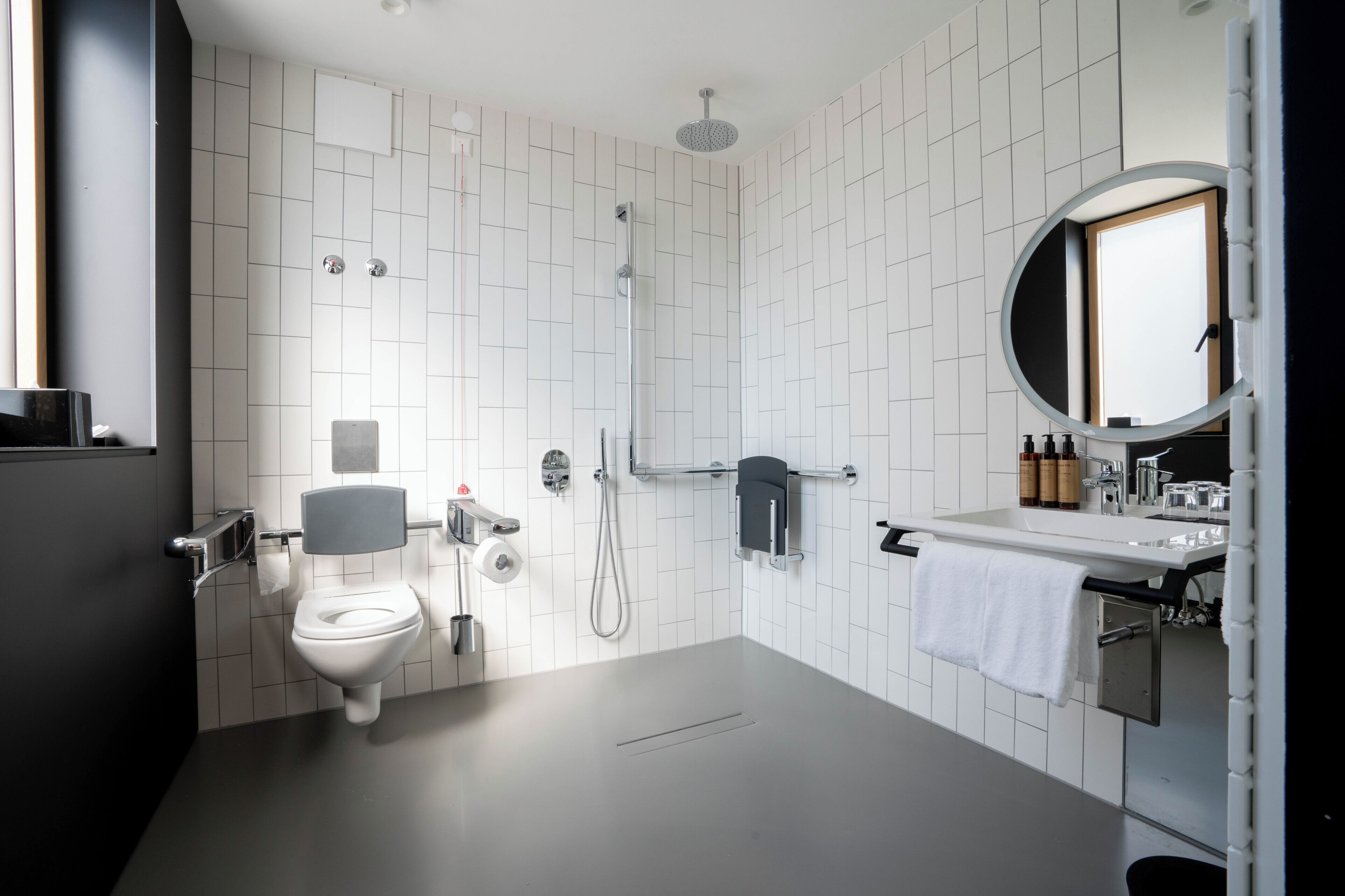 Een moderne badkamer met toilet, douche, wastafel en spiegel.