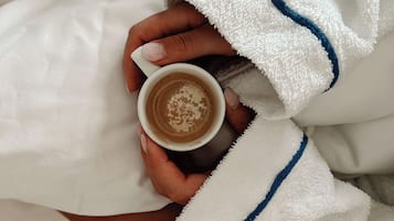 A person holding a cup of coffee with a white robe and blue trim.