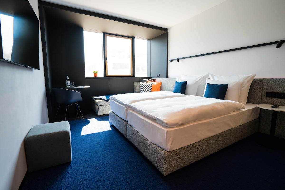 Ett modernt hotellrum med en stor säng, ett skrivbord och en liten sittgrupp.