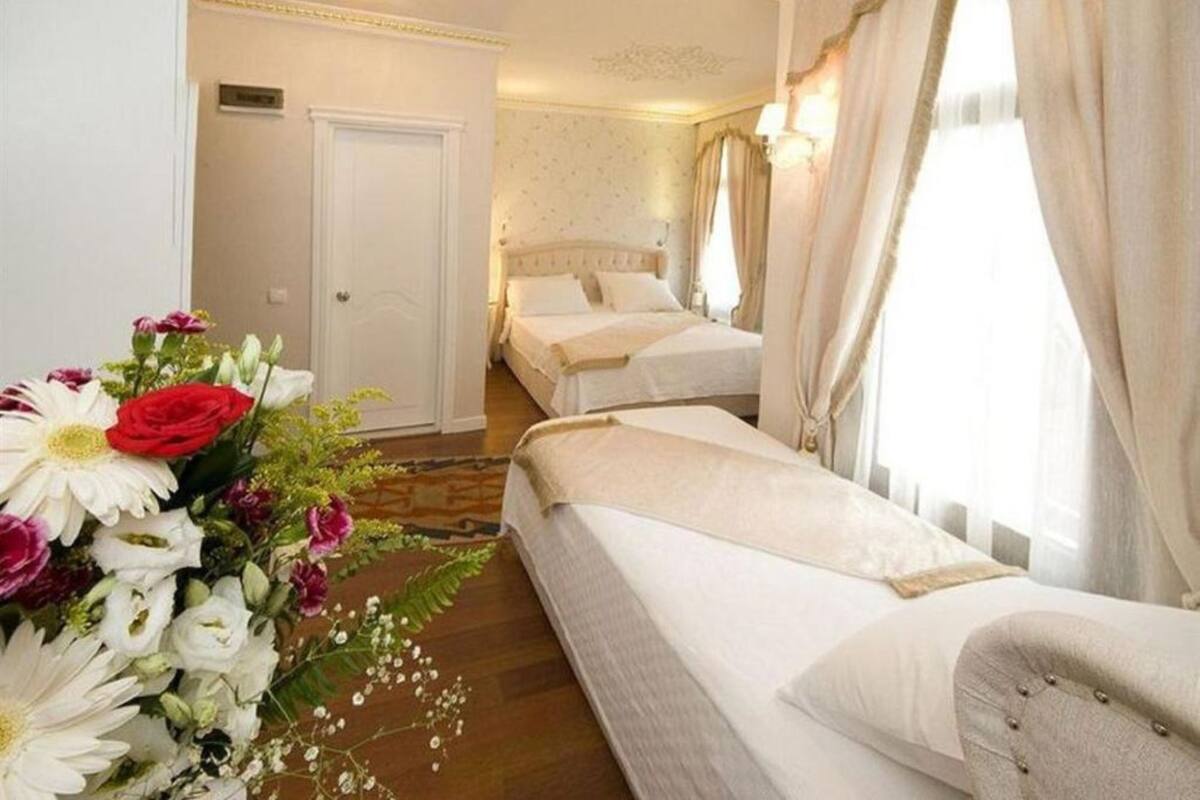 A hotel room with two beds, a floral arrangement, and a view of the hallway.