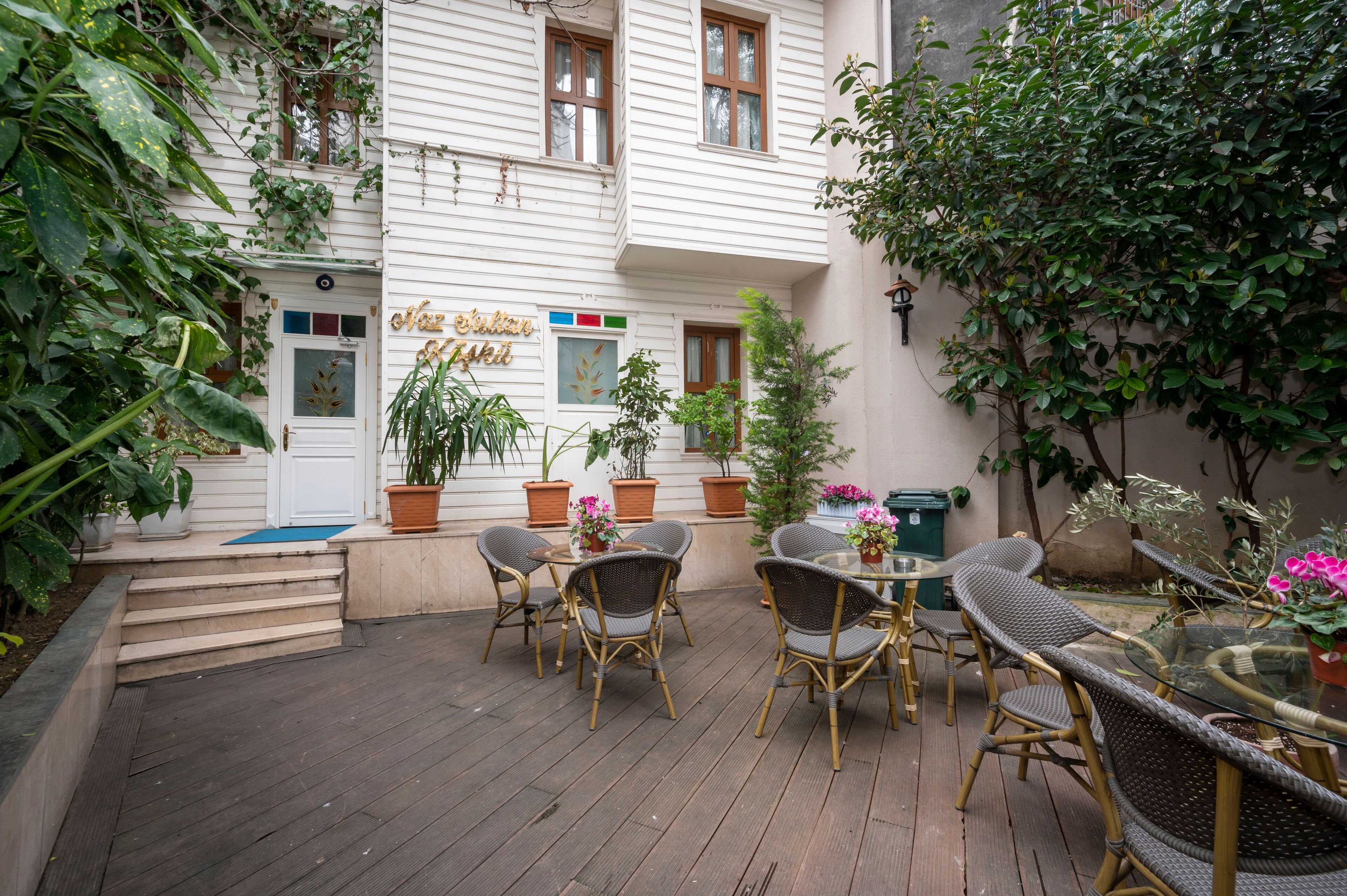 A courtyard with a white building, wicker furniture, and potted plants.