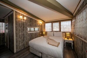 Un dormitorio con una cama grande, dos lámparas de noche, una mesita de noche y un espejo.