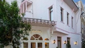 A white building with a balcony, a covered entrance, and two potted plants. - Fuat Bey Palace Hotel (Istanbul)