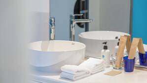A bathroom with a large white sink, a mirror, and a blue wall. - Tru by Hilton Viet Tri City Centre (Thanh Mieu)