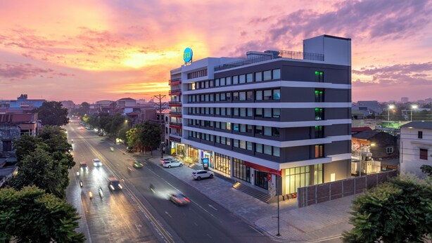 A multi-story hotel with a modern design, featuring a prominent sign on the top. - Tru by Hilton Viet Tri City Centre (Thanh Mieu)