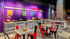 A breakfast area with a purple wall, a sign reading "TOPIT BREAKFAST," and various food items displayed. - Tru by Hilton Viet Tri City Centre (Thanh Mieu)