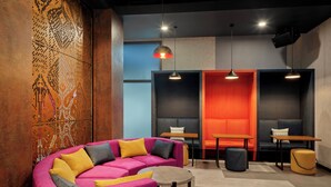 A modern lounge area with a pink sofa, multiple seating options, and pendant lighting. - Tru by Hilton Viet Tri City Centre (Thanh Mieu)