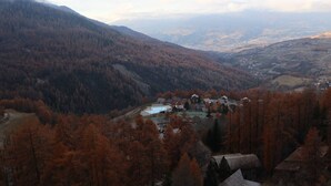 Un paysage montagneux aux couleurs automnales, avec un petit groupe de bâtiments et une vallée en contrebas.