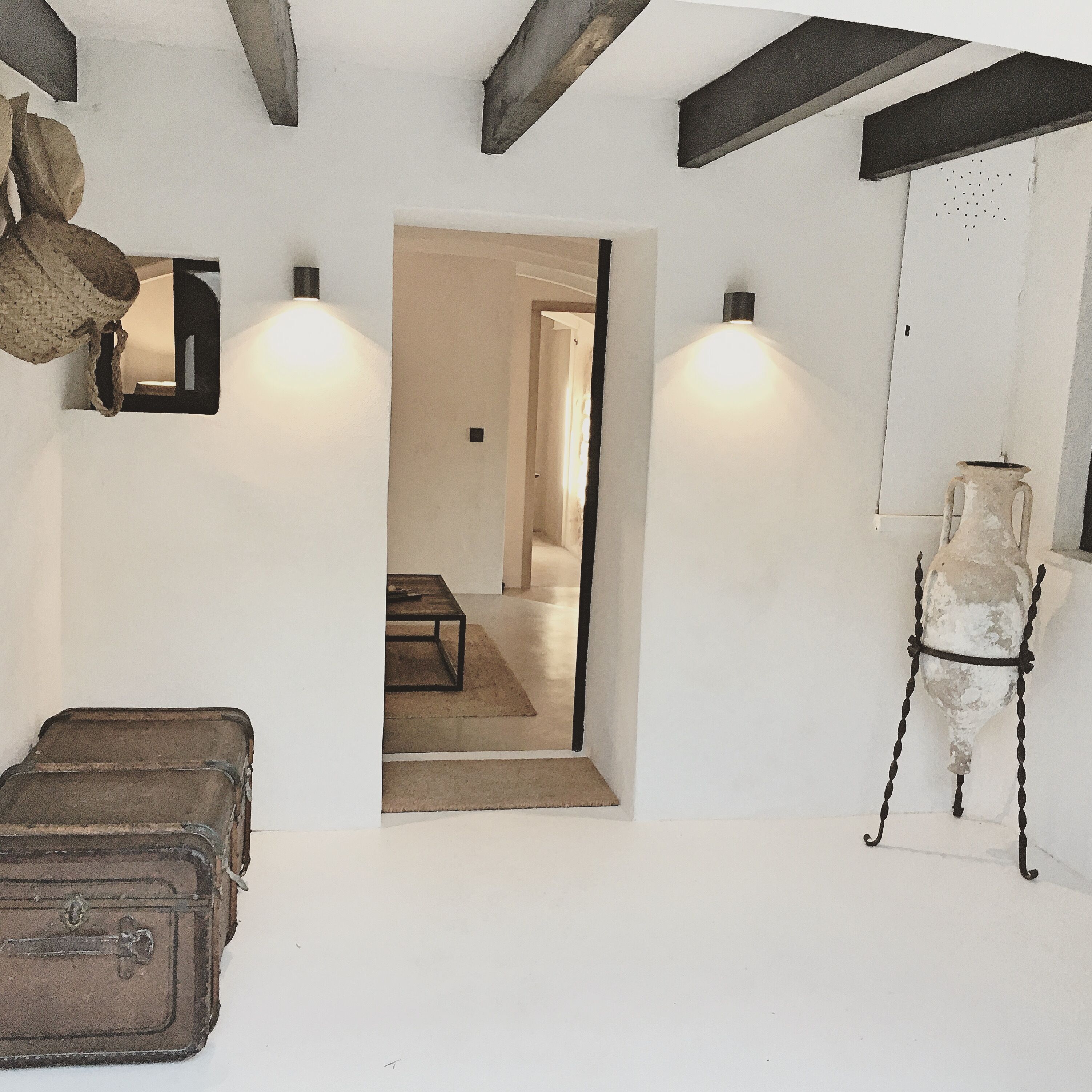 A room with a bed, a suitcase, a lamp, and a vase.