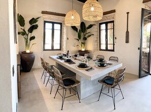 A dining area with a large island, wicker chairs, and hanging rattan lights. - My Rent House Mallorca [big house] (Cala Figuera)
