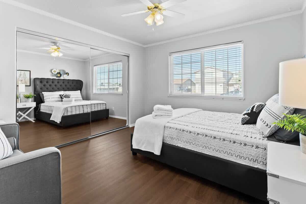 Une chambre à coucher moderne avec un grand lit, un ventilateur de plafond et un miroir.