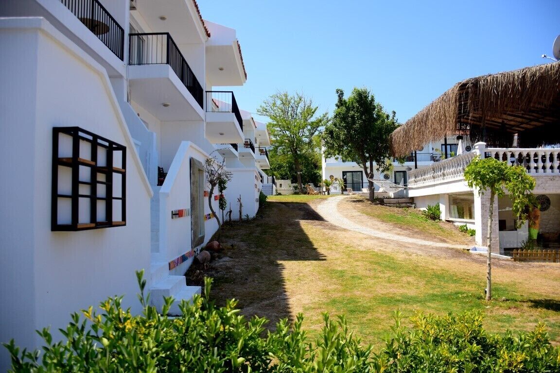 Un hotel moderno con paredes exteriores blancas, balcones y una estructura con techo de paja.