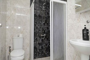 Un baño con inodoro, cabina de ducha y lavamanos.