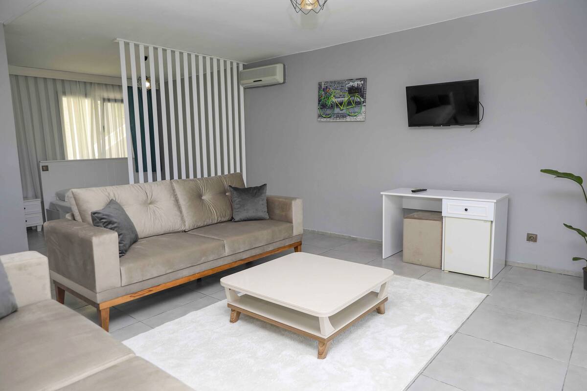 A modern living room with a sofa, a coffee table, a TV, and a desk.