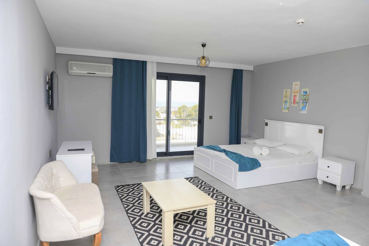 A modern bedroom with a bed, bedside tables, a desk, and a chair.