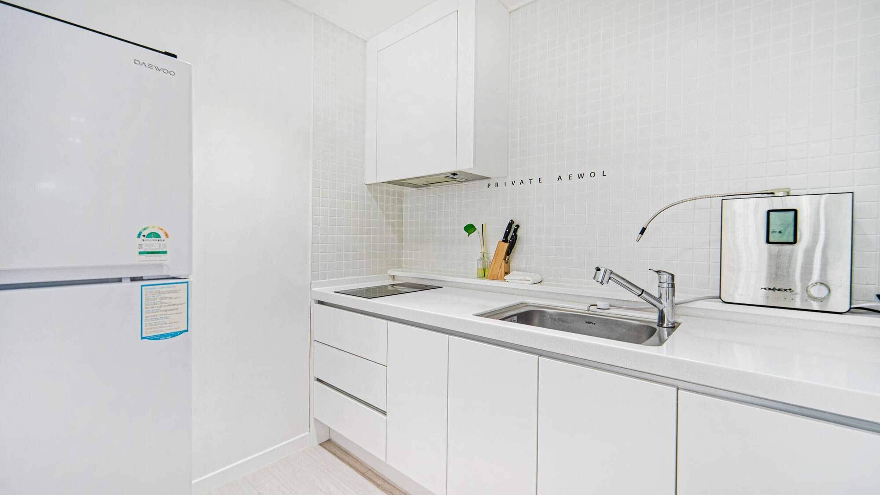 Una cocina moderna con armarios blancos, un lavamanos de acero inoxidable y un horno empotrado.