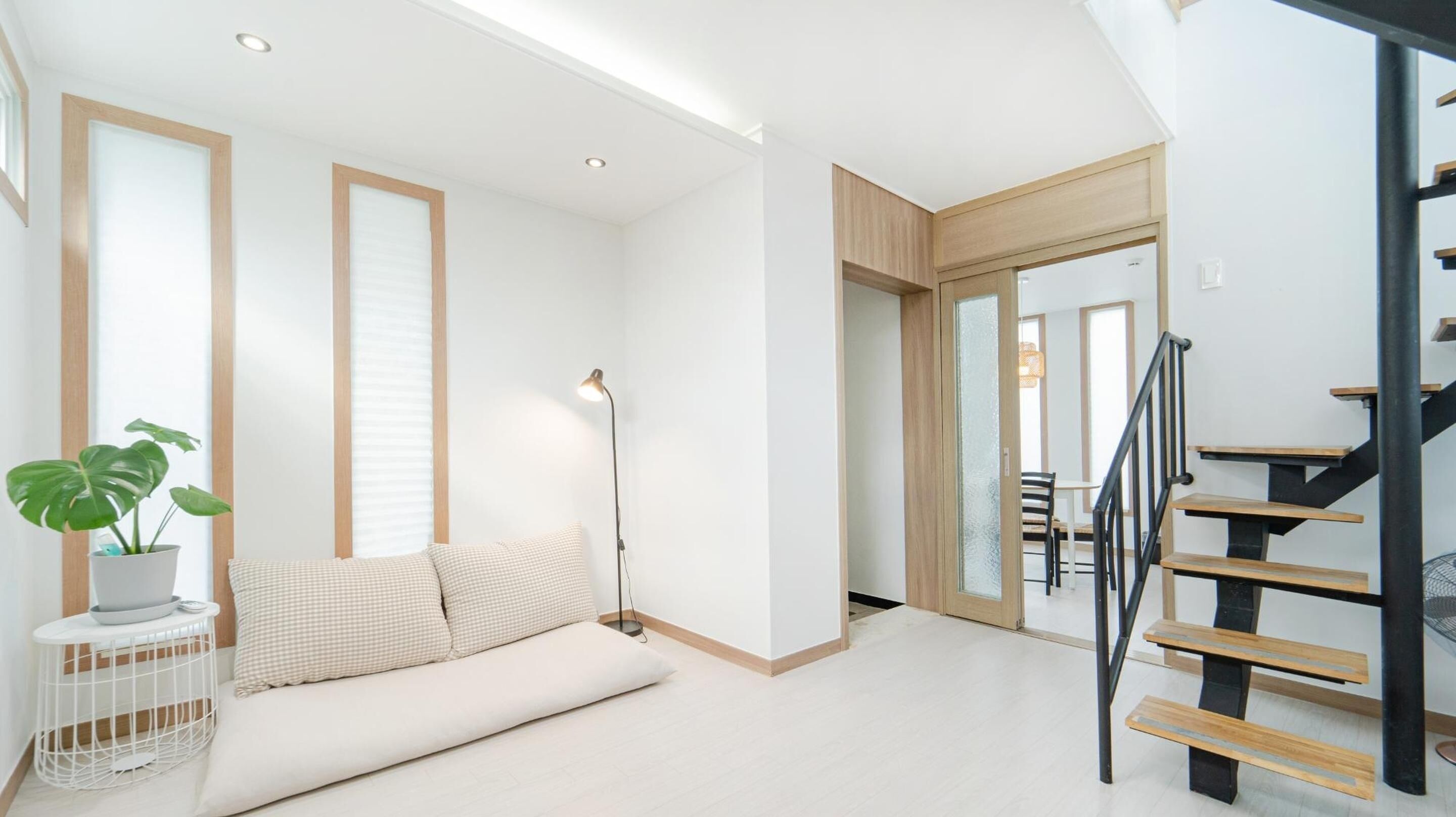 A modern living room with a sofa, a floor lamp, and a staircase.