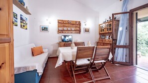A cozy room with a bed, a dining table with chairs, a TV, and a bookshelf.