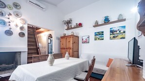 A dining area with a table set for two, a wooden cabinet, and a TV on a wooden stand.
