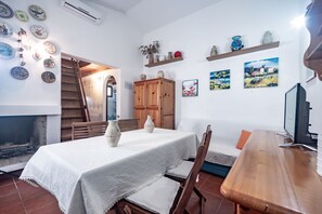 A dining area with a table set for two, a wooden cabinet, and a TV on a wooden stand.