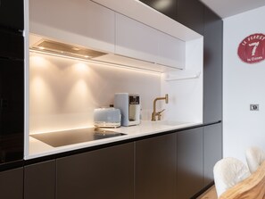 Cocina moderna con isla integrada, cafetera y grifo dorado.