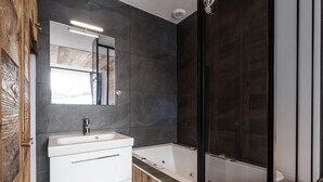 Ein modernes Badezimmer mit einem weißen Waschtisch, einem großen Spiegel und einer Duschkabine.
