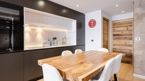 Eine moderne Küche mit Backofen, einer Kaffeemaschine und einem Holzespeisetisch mit Stühlen.