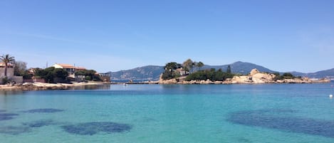 A coastal area with clear turquoise water, rocky shorelines, and buildings with red roofs.