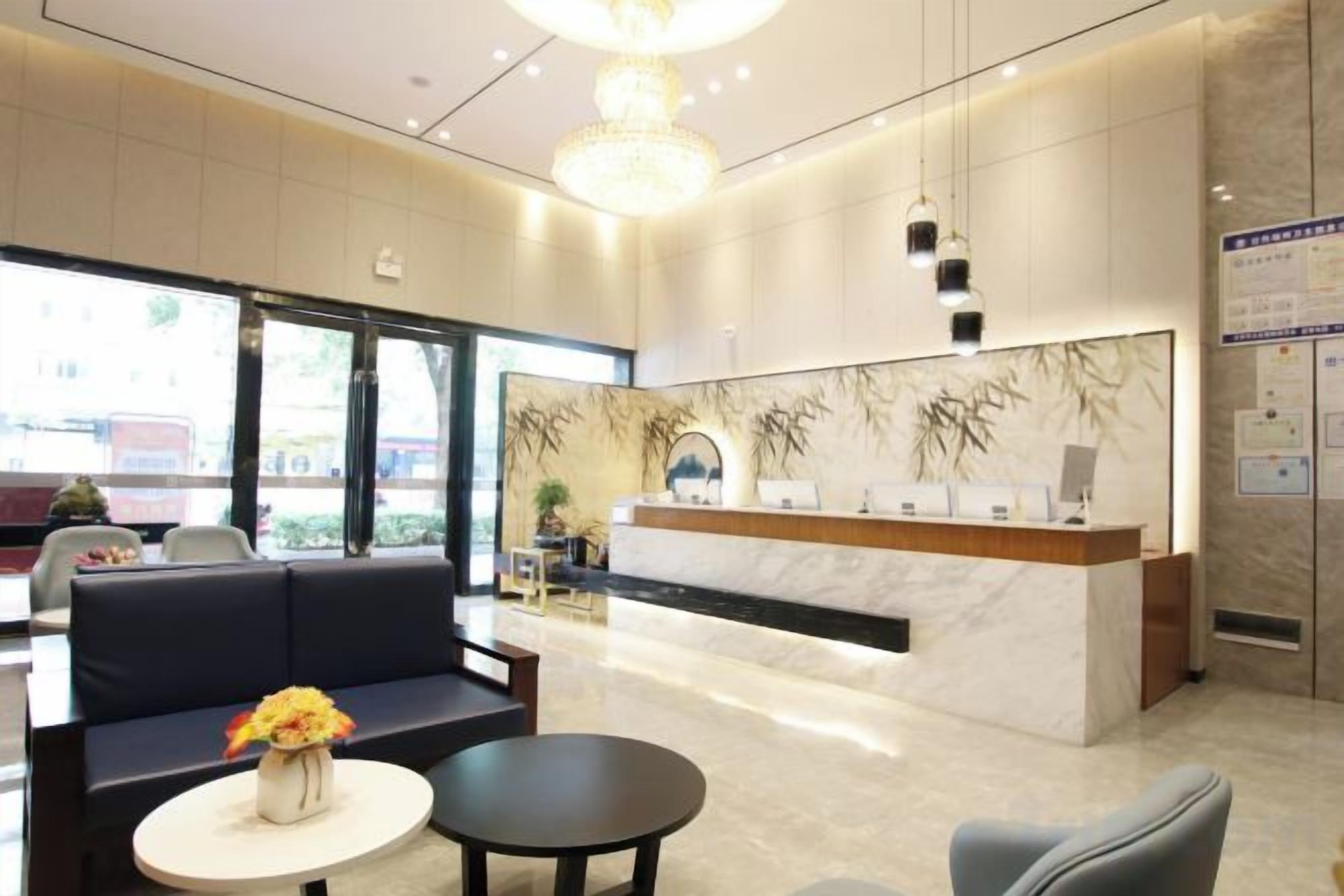 Un vestíbulo de hotel con mostrador de recepción, zona de estar y un candelabro.