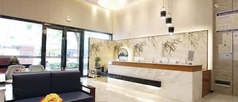 Un vestíbulo de hotel con mostrador de recepción, zona de estar y un candelabro.