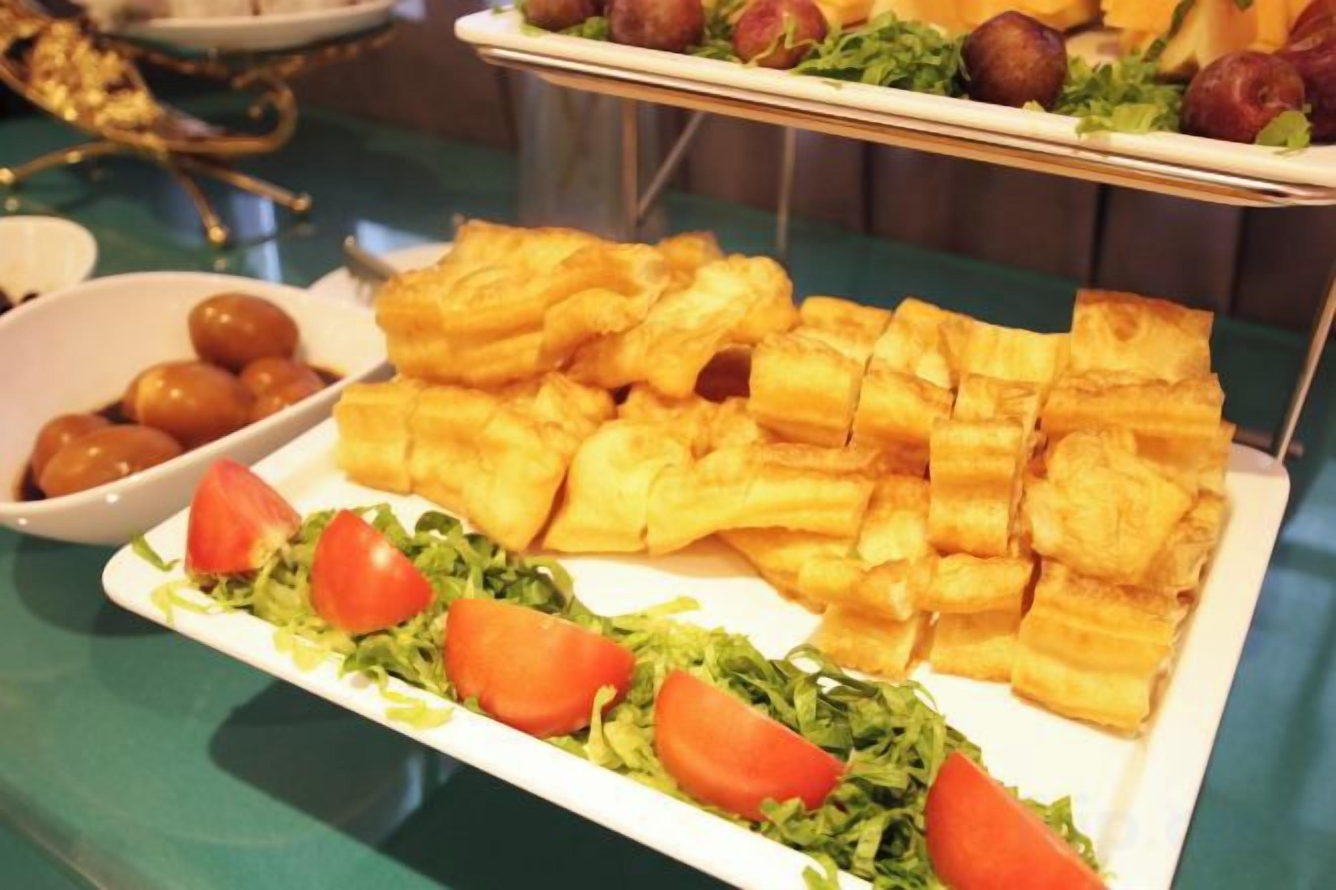 Una mesa de bufé con diversos alimentos, incluyendo pan y un bol de fruta.