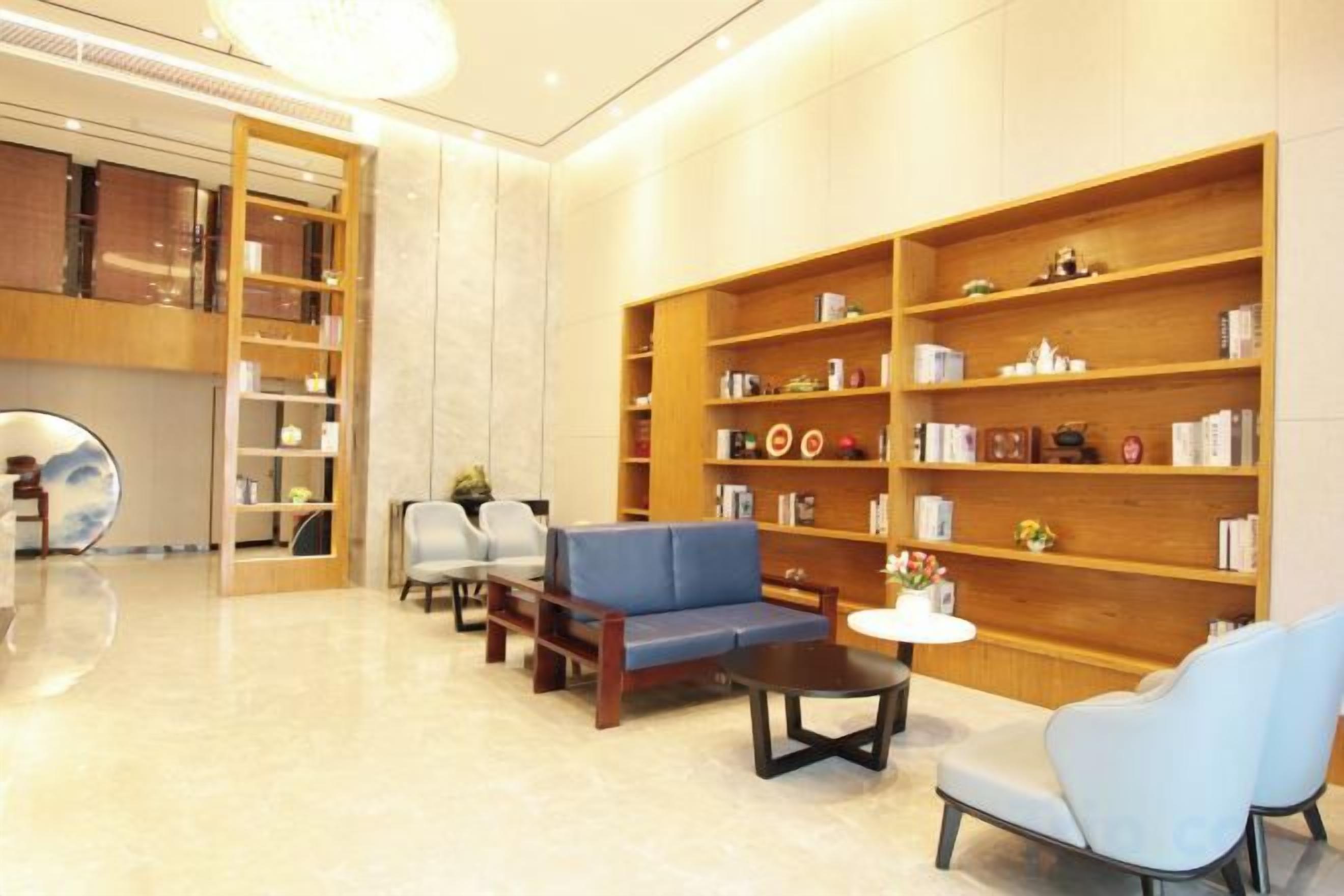A lobby with a blue sofa, wooden bookshelves, and a round table.