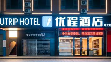 Un hotel con un letrero llamativo, una cafetería y una tienda con caracteres chinos.