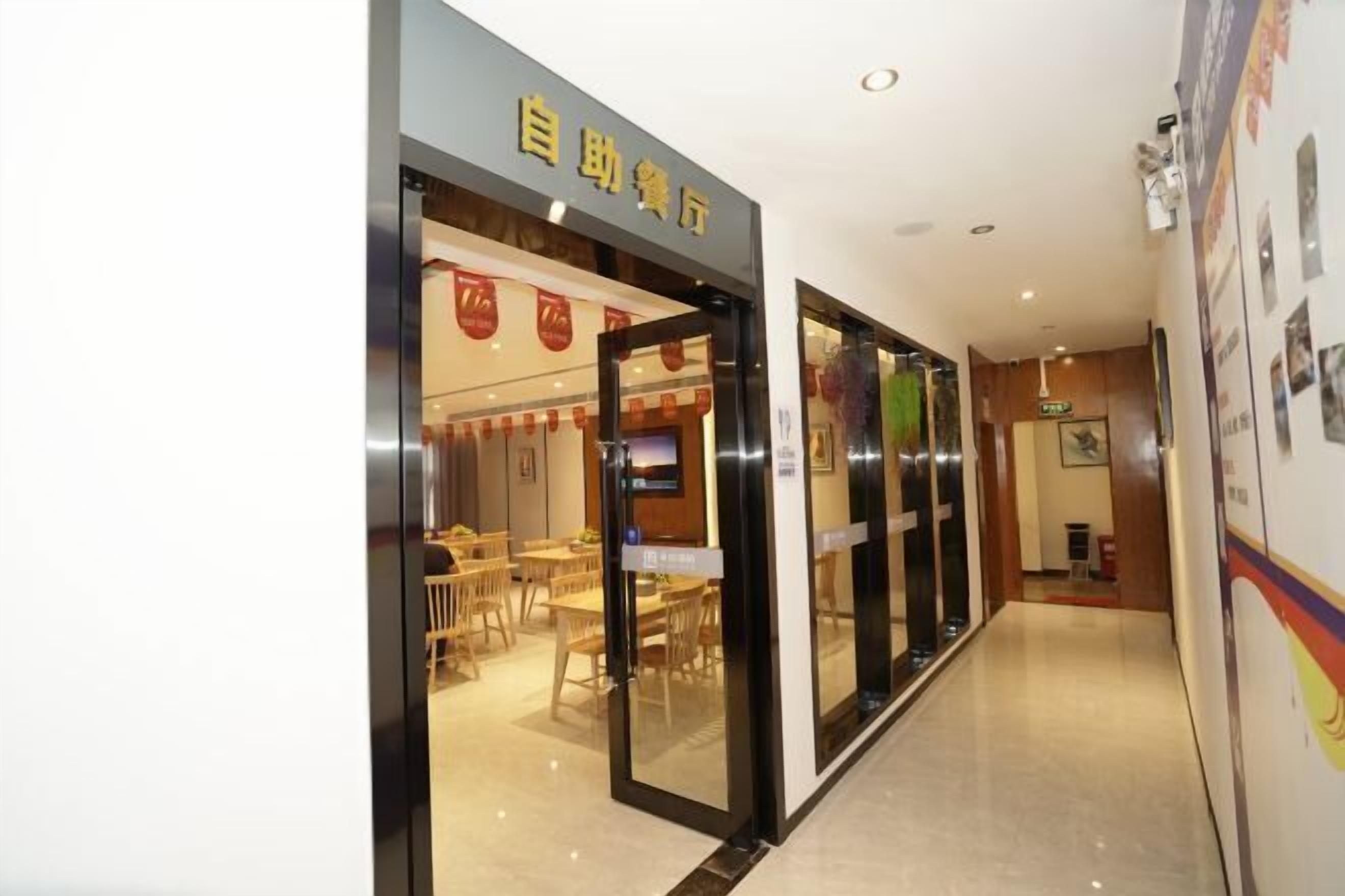 A hotel lobby with a reception desk, a seating area with tables and chairs, and a corridor leading to other parts of the hotel.