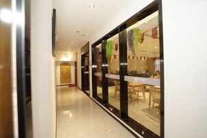 Un pasillo con un muro de cristal que conduce a un comedor con mesas y sillas.
