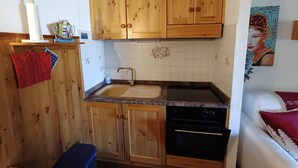 A compact kitchen with wooden cabinets, a sink, and a dishwasher. - Studio for 4 with terrace, garden and parking (Montgenèvre)