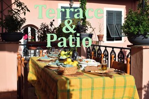 Eine Terrasse mit Esstisch, umgeben von Topfpflanzen und einem Geländer.