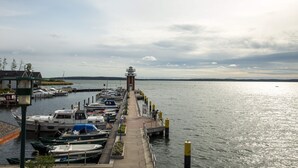 Un puerto deportivo con barcos amarrados, un faro y un cielo despejado.