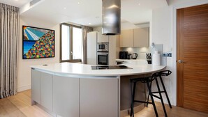 A modern kitchen with a central island, built-in appliances, and a large window. - Westbourne Curve, by Veeve (London)