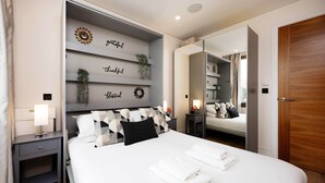 A modern hotel room with a large bed, a nightstand, a mirror, and a wall with decorative items. - Westbourne Curve, by Veeve (London)