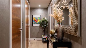 A hallway with wooden doors, a console table with a vase, and a mirror. - Westbourne Curve, by Veeve (London)