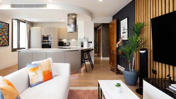 A modern living room with a white sofa, a coffee table, and a large potted plant. - Westbourne Curve, by Veeve (London)