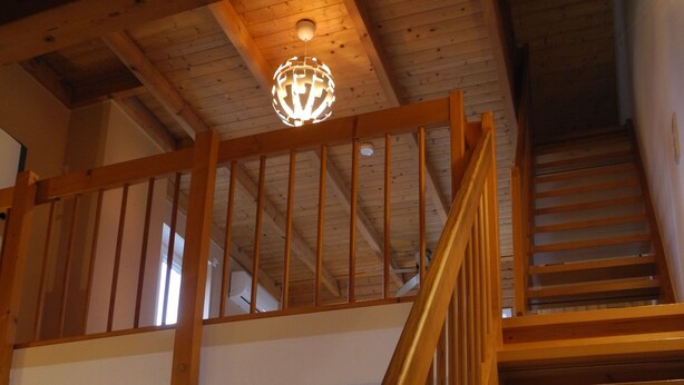 Una escalera de madera que sube a un nivel superior con barandilla de madera.