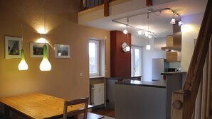 Una cocina moderna con una mesa y sillas de madera, una isla integrada e iluminación colgante.