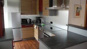 Una cocina moderna con electrodomésticos de acero inoxidable, armarios de madera y una encimera gris.