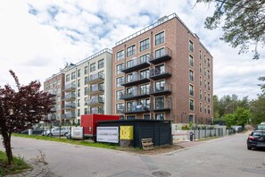 Un edificio residencial de varios pisos con balcones, una entrada con reja y un área de estacionamiento.