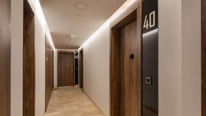 A modern hotel hallway with wooden doors, numbered doors, and a carpeted floor.
